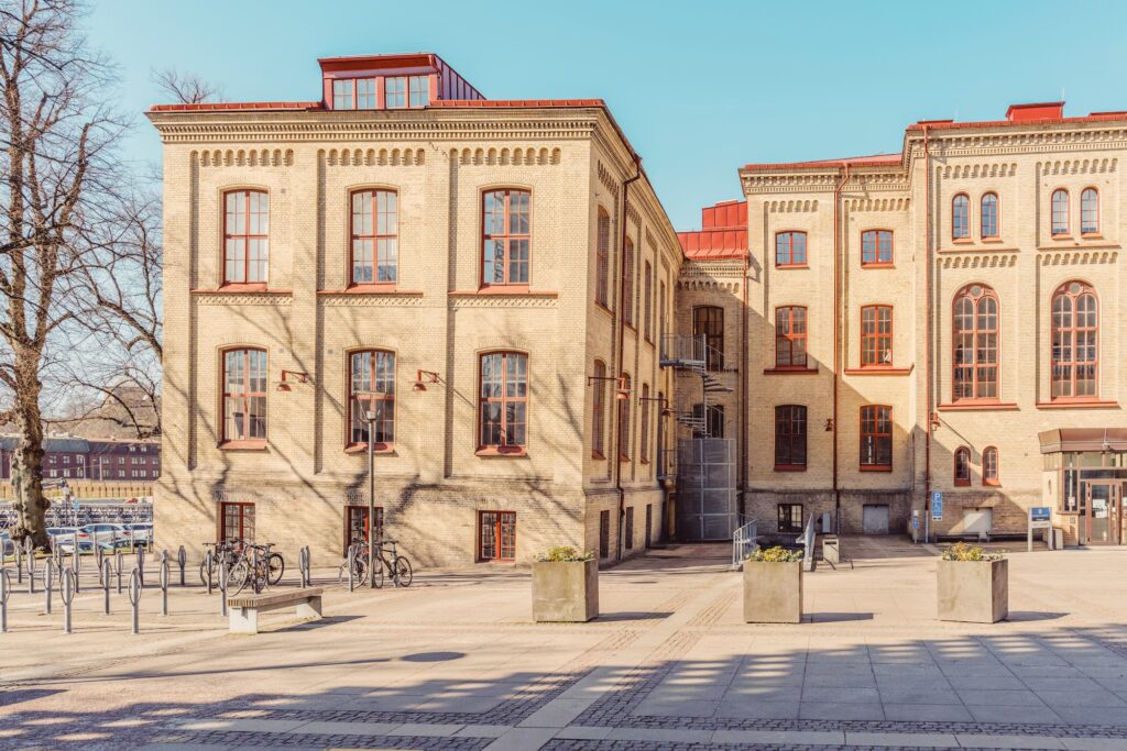 Gul tegelfasad med stora fönster och innergård vid Pedagogen i Göteborg